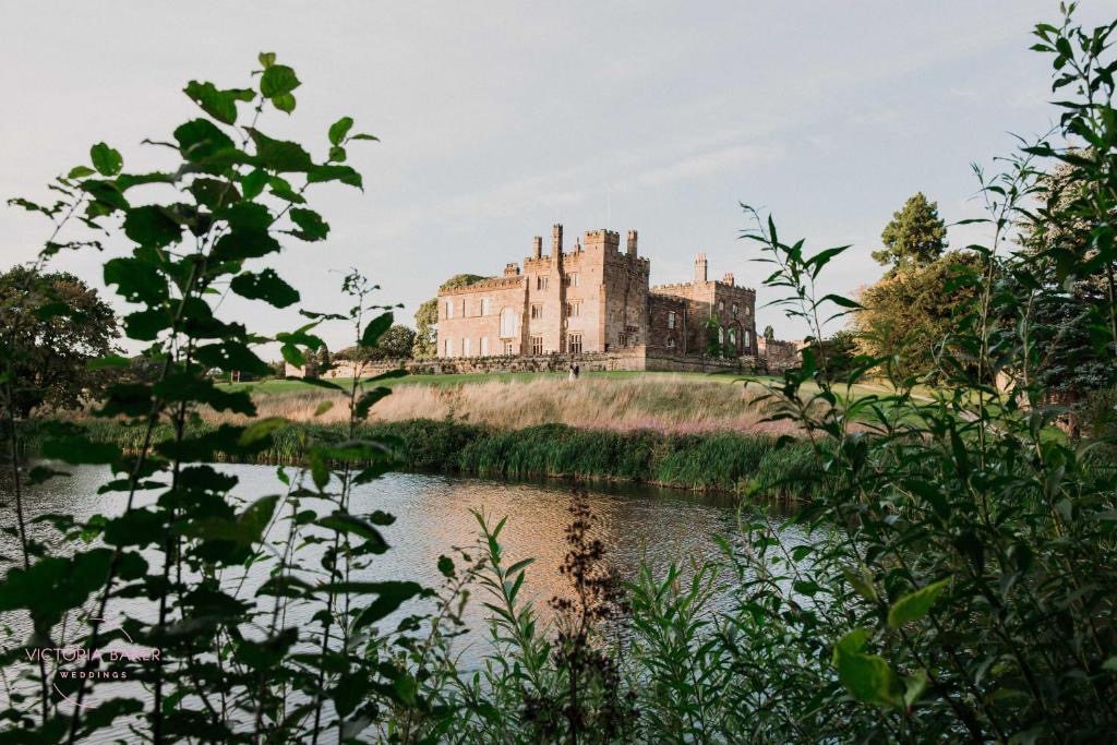 Ripley Castle across the lake, framed by leaves in the foreground.